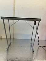 Front view of foldable table showing metal legs and frame with electric board surface.