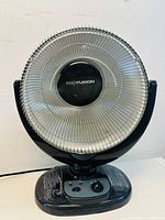 Front view of Pro Fusion room heater showing circular metal guard and control panel with knob and indicator lights.