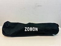 Folded microphone stand inside black carrying bag with Zomon logo