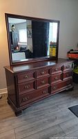 Front view of the solid mahogany long dresser with attached large mirror in a room with wood floor.