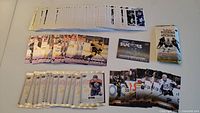 Full layout showing over 120 hockey cards spread on a white surface, with gold foil backs visible on some cards, a group of base and subset cards grouped in front, and one unopened pack to the right.