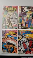 Four Marvel comic books displayed in two columns, showing full front covers, bagged and boarded. Titles include Damage Control, The Silver Surfer, and Marvel Adventures.