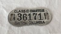 Oval metal license plate from 1961 British Columbia Class C Chauffeur with license number 36171