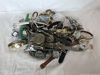Pile of over 50 assorted wristwatches and pocket watches in mixed styles and bands, including metal, leather, and fabric straps. Watches vary in face shapes and designs, some in plastic bags, all untested.