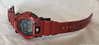 Side angled view showing the red resin case, strap, and digital display of the Casio G-Shock watch.