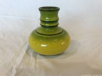 Front view of the yellow-green glazed pottery vase showing its shape and color gradient.