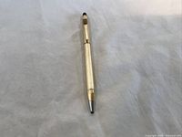 Gold filled Cross pen lying flat on white surface, clear view of tip and clip.