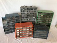 Wide shot showing 5 multi-drawer parts cabinets in different colors with clear drawers containing assorted hardware parts