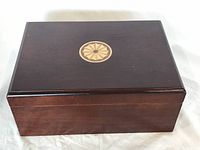 Closed view of the wooden humidor box showing the decorative circular inlay on the top lid.