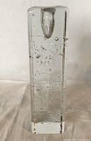 Full view of tall rectangular clear glass candlestick with bubbles inside and a candle holder at the top.