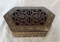 Top view of closed hexagonal jewellery box showing dark wood lattice design and mother of pearl marquetry inlay around edges.