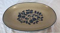 Top view of the oval serving platter showing the blue folk art floral design on beige background with a blue rim line.