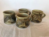Four ceramic mugs displayed together showing their shape and glaze pattern