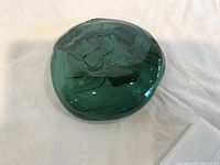 Green glass bowl with smooth round organic shape, photo showing top and side view on neutral background.