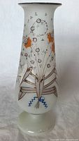 Full view of white opaque glass vase with abstract hand painted floral motif in orange, gray, blue, and purple.