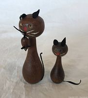 Photo of front view of teak MCM cat holding attached mouse and separate smaller mouse figurine, showing hand painted facial details and leather ears and tails.
