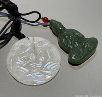 Photo showing both jade pendants - green seated Buddha and white circular double gold fish.