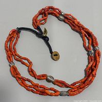 Full view of the coral beads necklace showing multiple strands and silver beads with button clasp.
