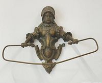 Front view of brass towel rack with detailed female figure and curved towel rod attached to hands