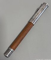 Full view of vintage pen showing silver cap, wood barrel, and engraved initials AAM.