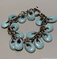 Front view of the entire bracelet laid flat showing the sterling silver chain with light blue ceramic donut-shaped charms.
