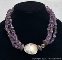 Front view of purple amethyst chip bead necklace with gold spacer beads and large mother of pearl clasp displayed on a black bust.