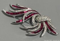 Front view of the vintage Boucher brooch showing clear and red rhinestones in a swirling feather design.