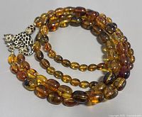 Full view of coiled amber-colored lucite bead necklace with leopard clasp