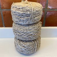 Photo showing three large pre-wound skeins stacked vertically, displaying the yarn texture and natural color variations