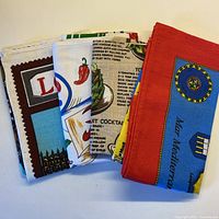 Four folded tea towels showing various regional prints and recipe designs