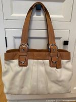 Front view of cream leather Coach handbag with caramel leather handles and trimming.