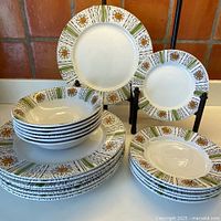 Full set of 20 Kathie Winkle Ironstone dishes including 8 dinner plates, 6 luncheon plates, and 6 cereal bowls arranged and stacked.