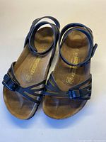 Top view of pair of black Birkenstock sandals showing adjustable buckled ankle and toe straps on suede footbed.