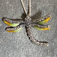 Full view of sterling silver dragonfly pendant necklace showing the pendant and chain on a dark background.