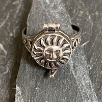 Top view of sterling silver ring showing hinged lid with sun face design and surrounding sun rays, placement of hinge visible at top.