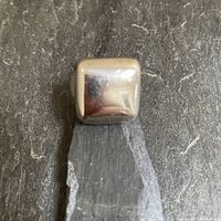 Top view of the smooth, rounded square sterling silver ring face on gray stone background.