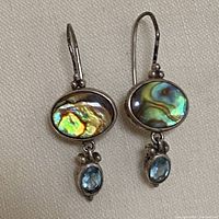 Photo showing pair of vintage sterling silver earrings with iridescent oval abalone shell stones and light blue dangling stones