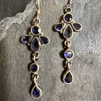 Full view of both earrings showing linked drop design with faceted amethyst stones in sterling silver bezels.