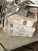 Stack of four white Nintendo Wii consoles with power cable on top