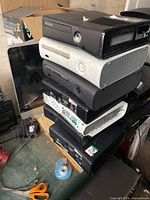 Stacked view of eight Xbox 360 consoles, mix of original and Slim versions