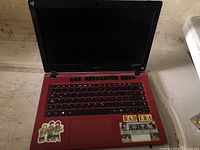 Laptop open showing keyboard, screen, stickers