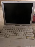 Apple iBook G4 laptop open showing black screen, keyboard