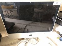 Front view of Apple iMac showing screen, bezel, stand and attached cable