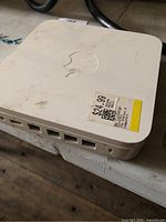 Top and rear view of Apple AirPort Extreme router showing ports and surface wear