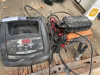 Three chargers grouped: NOCO Genius 10, orange metal automotive charger, black plastic docking charger