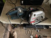 Top view of SkilSaw circular saw and teal belt sander on table