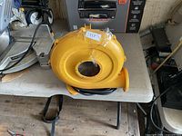 Yellow electric blower with cord on table