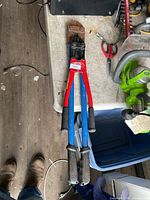 Full view of bolt cutters showing cutting head, red and blue handles, black grips