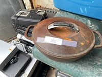 Top view of oval cast iron Dutch oven with lid, visible rust, stainless KitchenAid handle