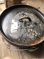 Cast iron lid with raised lettering and loop handle